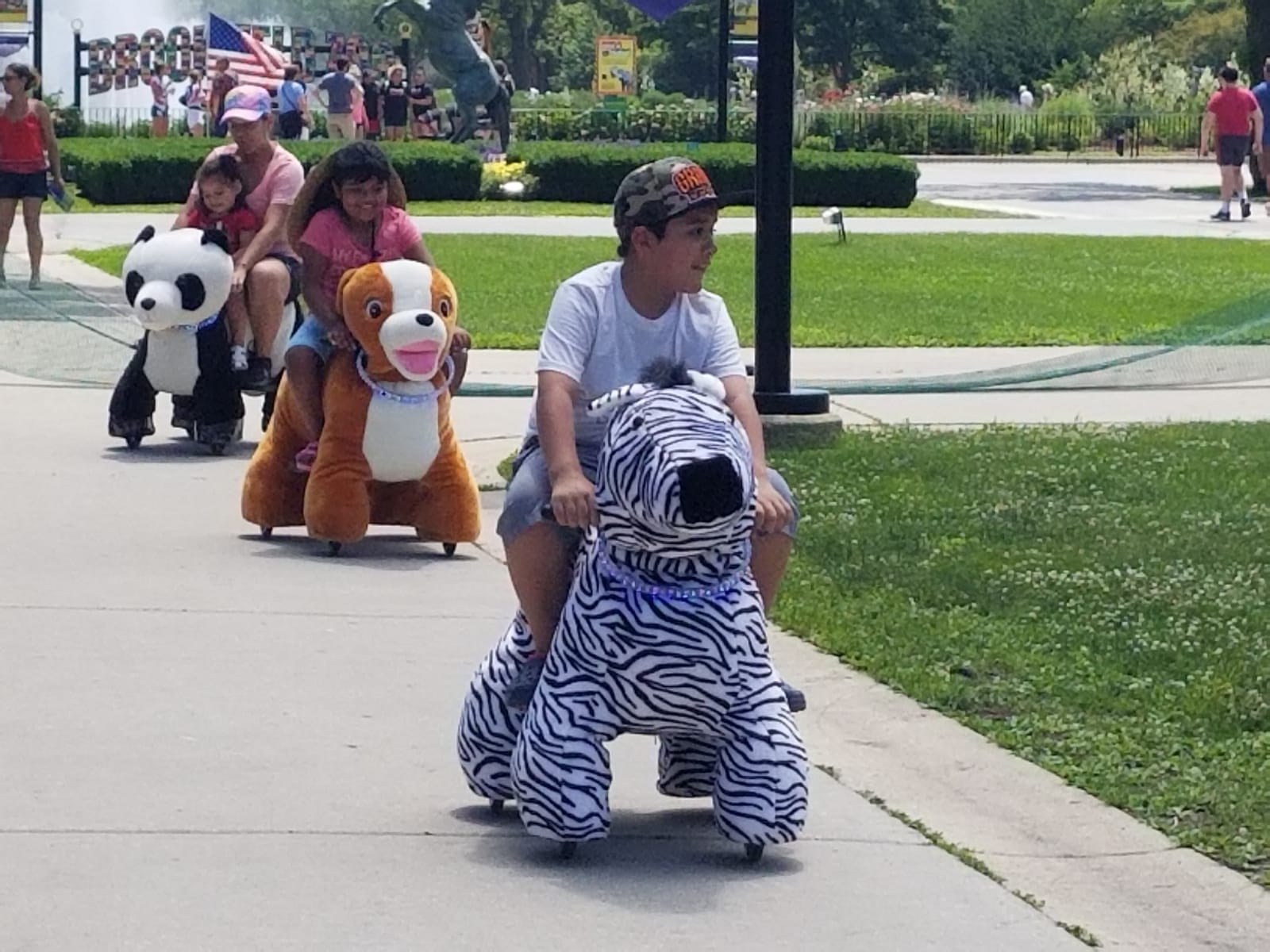 Guests enjoying zebra, lion, and panda animal rides outdoors